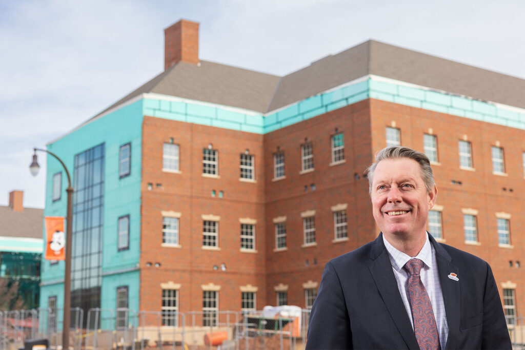 Dr. Jayson Lusk stands in front of the under-construction agricultural hall at Oklahoma State University.